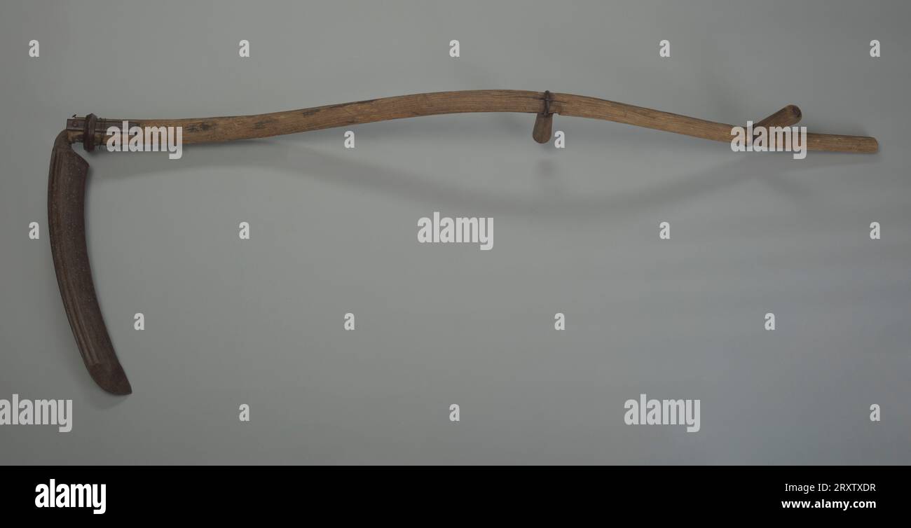 Un scythe en acier avec une poignée en bois appartenant à George Madison. Le scythe est constitué d'une lame métallique attachée à un arbre en bois incurvé appelé un escarath. La lame est fixée avec une bague de fixation en métal, des clous et du fil. La couronne est dotée de deux poignées en bois. Chaque poignée est orientée différemment. Banque D'Images