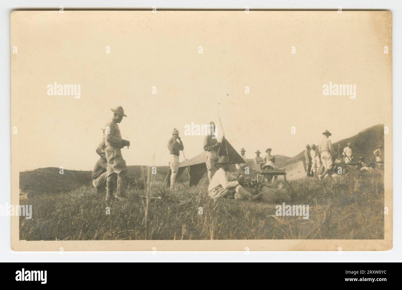 Carte postale photographique en gélatine d'argent d'un grand groupe de soldats, dont Charles Wilbur Rogan, entourant un campement dans un champ herbeux. Banque D'Images