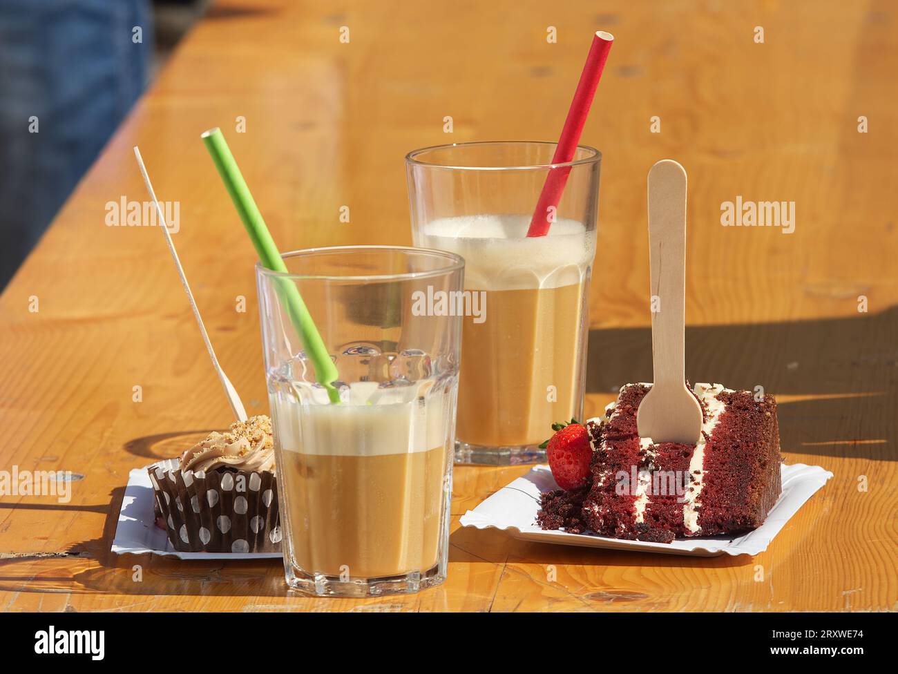 Deux gâteaux, une tranche de gâteau et un muffin avec deux verres de café glacé sur une table dans une cafétéria de rue au marché fermier. Banque D'Images