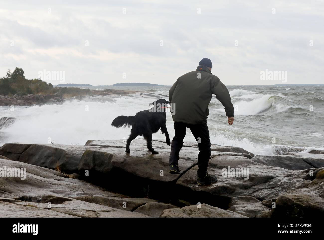 Un homme et un rocher debout contre le vent sur le bord de la mer Banque D'Images