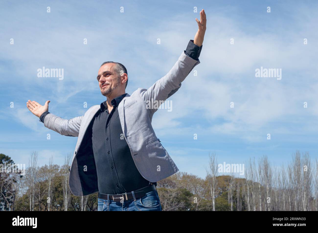 homme d'affaires caucasien français avec barbe et vêtements élégants, heureux gagnant célébrant ses gains financiers debout à l'extérieur à bras ouverts, espace de copie Banque D'Images