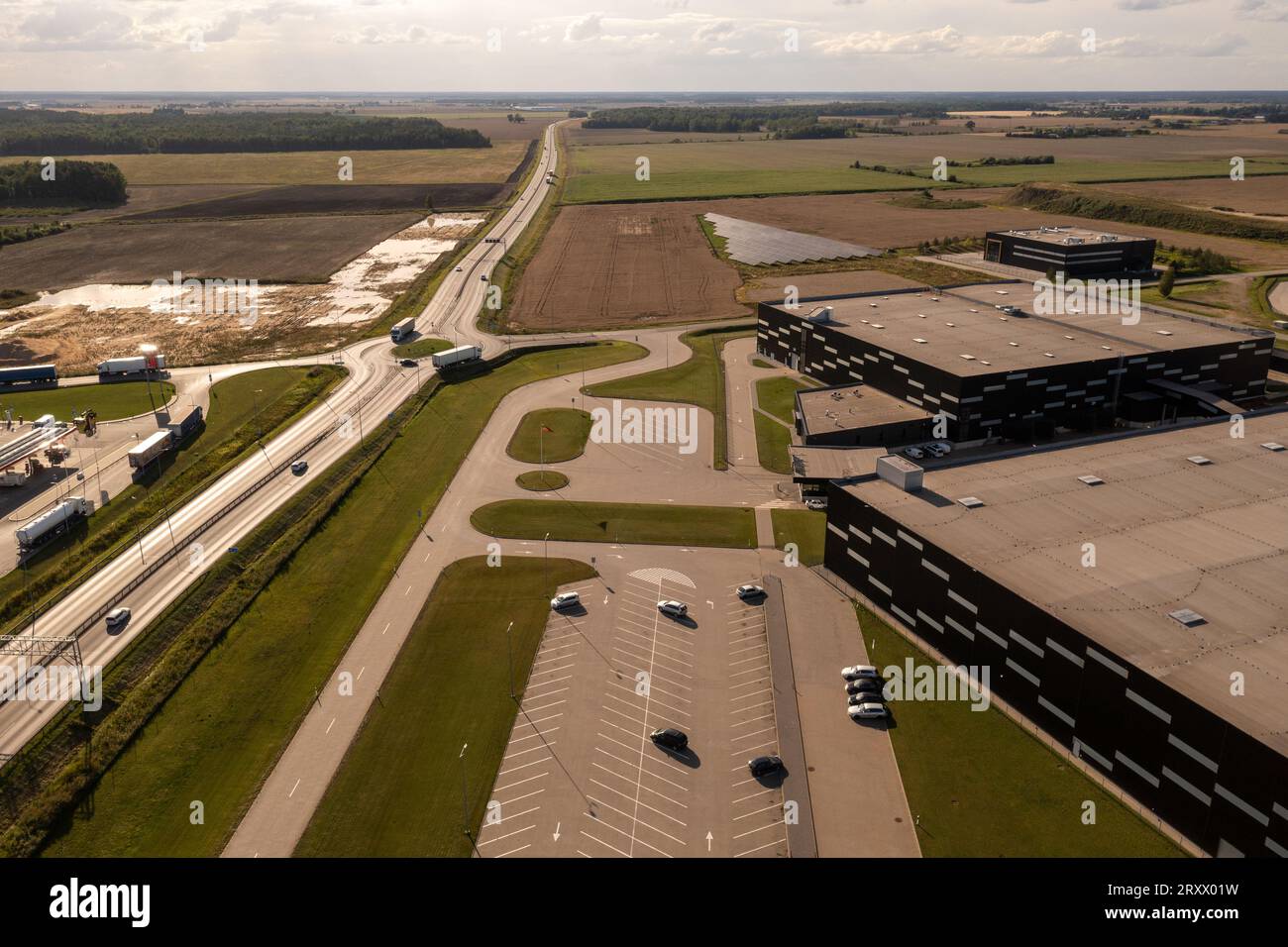 Photographie par drone des entrepôts logistiques, des camions et de la route routière pendant la journée d'été. Banque D'Images