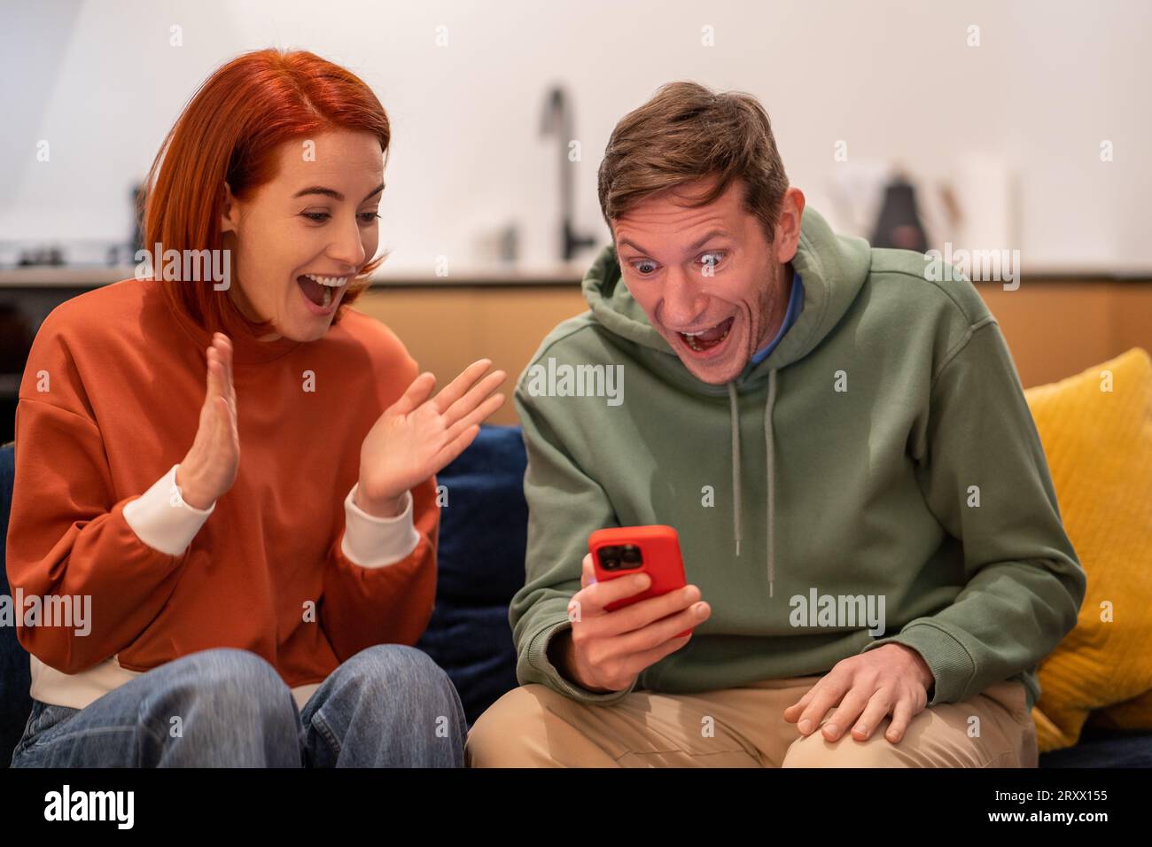 Joyeux jeune couple joyeux du millénaire heureux de regarder l'écran du téléphone crier avec joie Banque D'Images