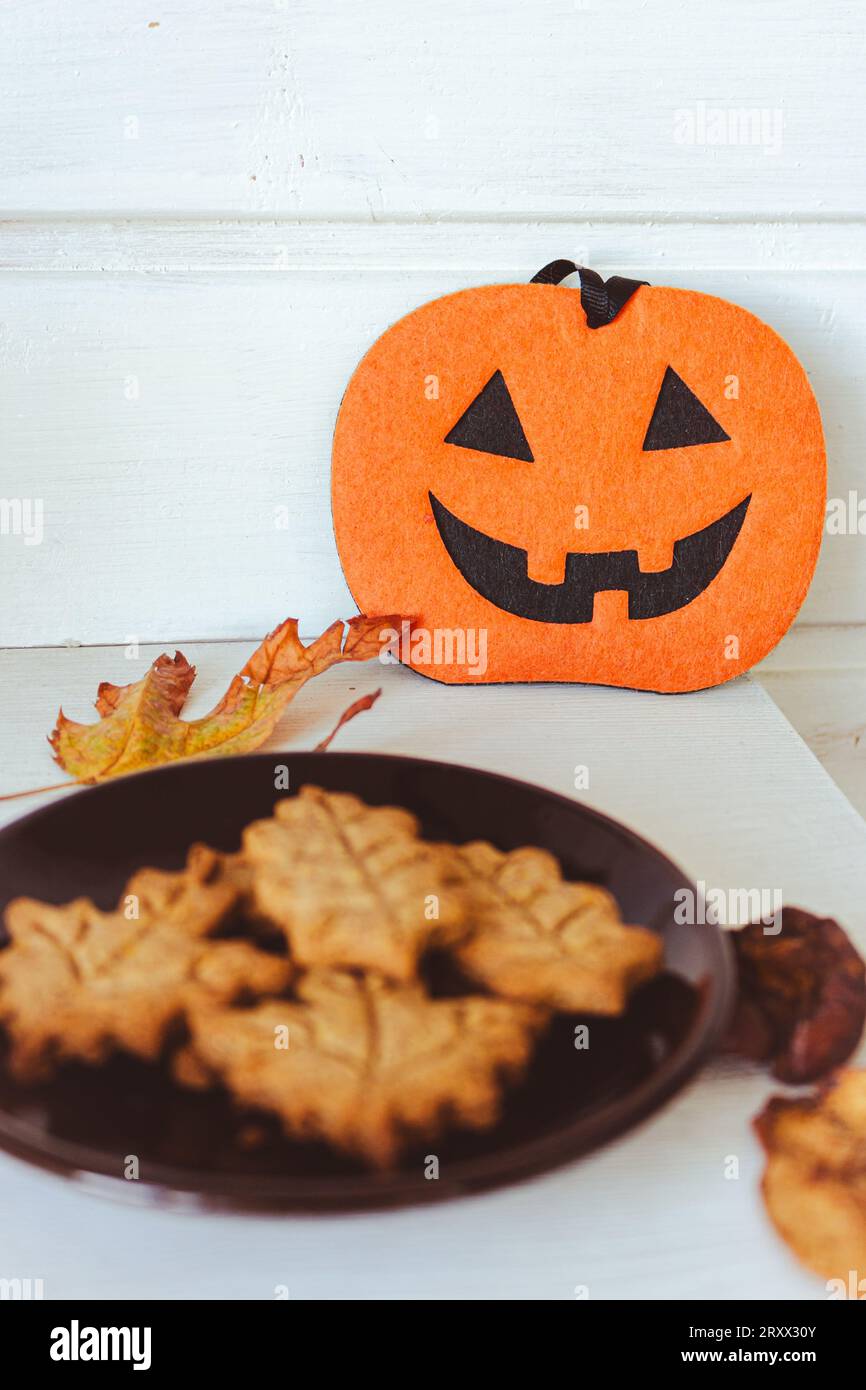 Biscuits à la citrouille d'Halloween et feuilles d'automne. Décoration Halloween. Trick ou Treat. Nature morte traditionnelle d'octobre. Citrouille effrayante et biscuits. Banque D'Images