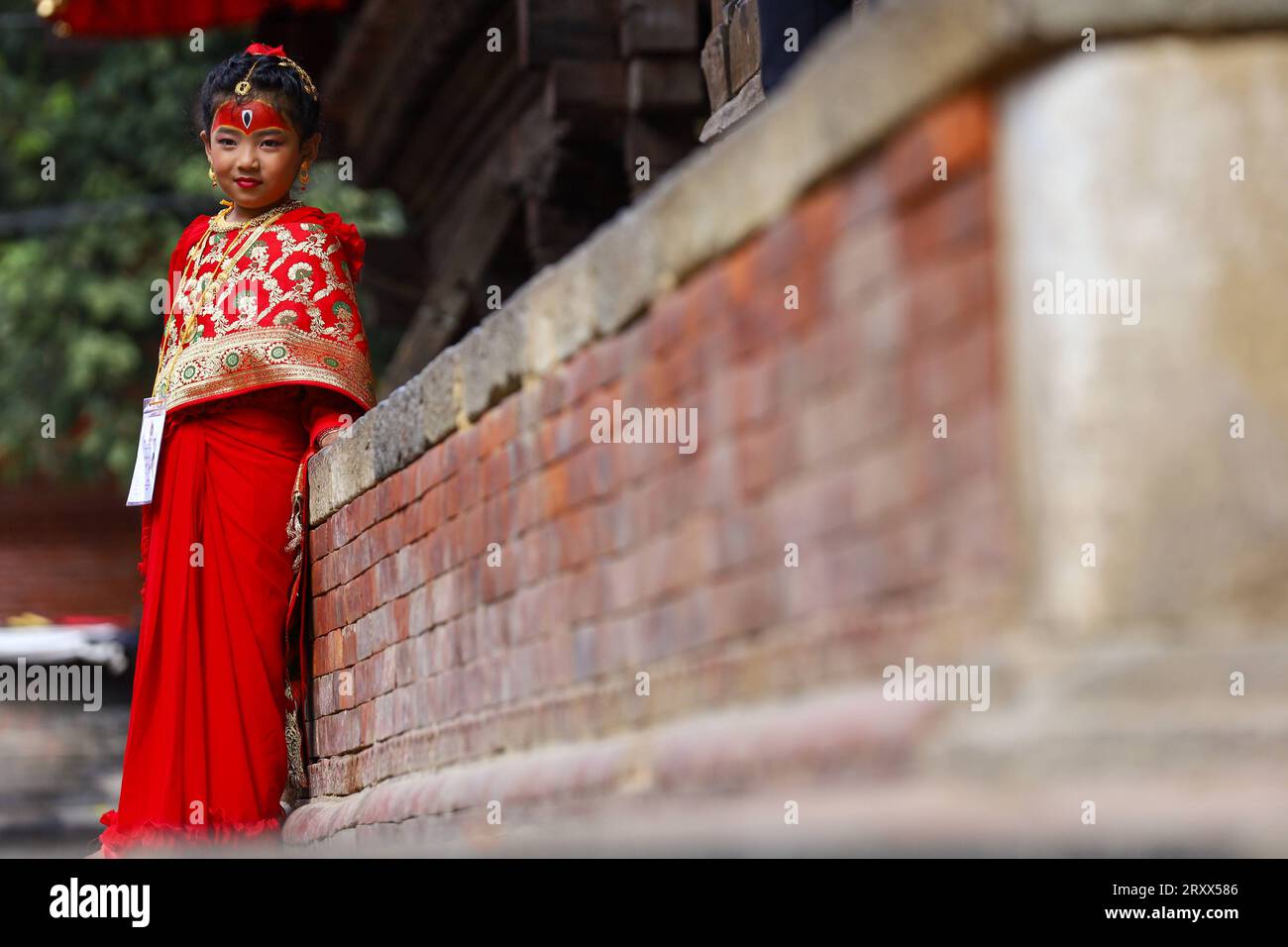 Kumari Pooja au Népal Une jeune fille népalaise pré-pubère pose pour une photo alors qu'elle assiste à la messe Kumari Pooja organisée à Basantapur Durbar Sqaure - un site du patrimoine mondial de l'UNESCO dans la capitale népalaise Katmandou. Vêtues de robes rouges, la déesse vivante Kumari Newa : les filles s'assoient en ligne pour être adorées tour à tour pour conjurer la malchance et les maladies. Les filles pré-pubères sont adorées chaque année inn la nation himalayenne comme incarnations terrestres de l'énergie féminine divine, manifestations de la déesse connue sous le nom Taleju Bhawani, le nom népalais de la déesse Durga. Droit d'auteur : xSubashxShresthax Banque D'Images