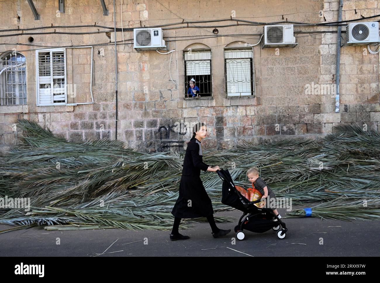 Une fille ultra-orthodoxe pousse une poussette devant les branches de palmier utilisées pendant la fête juive de Soukcot, la fête des Tabernacles, à Mea Shearim à Jérusalem, le mercredi 27 septembre 2023. Les Juifs religieux construisent des huttes temporaires, ou sukkahs, pour commémorer les 40 ans que les Israélites ont erré dans le désert après leur exode d'Egypte. Photo de Debbie Hill/ UPI Banque D'Images