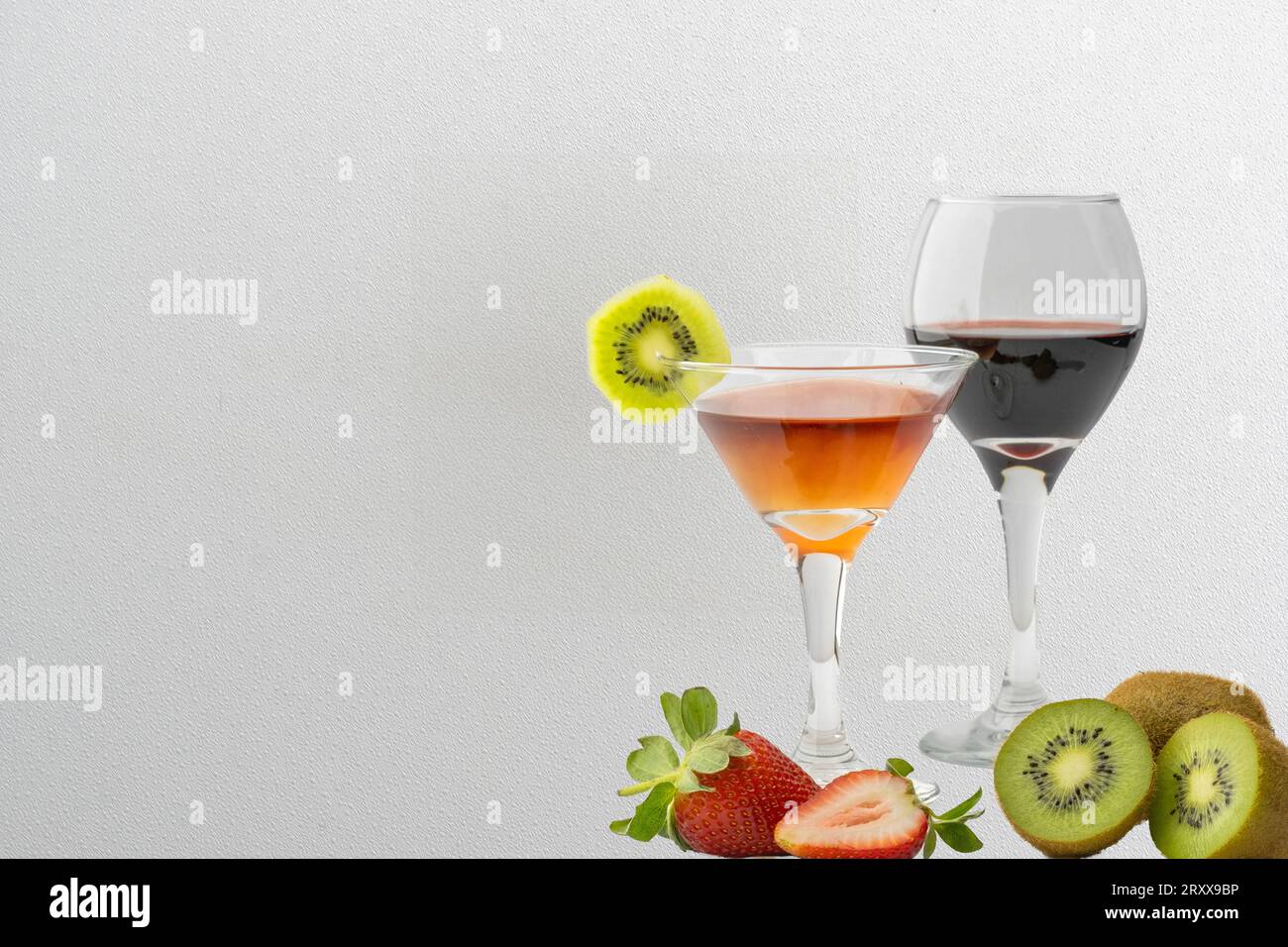 Un arrangement visuellement attrayant de fraises vibrantes et kiwi, complété par des verres de vin rouge et des cocktails ornés de garniture, tous ensemble aga Banque D'Images