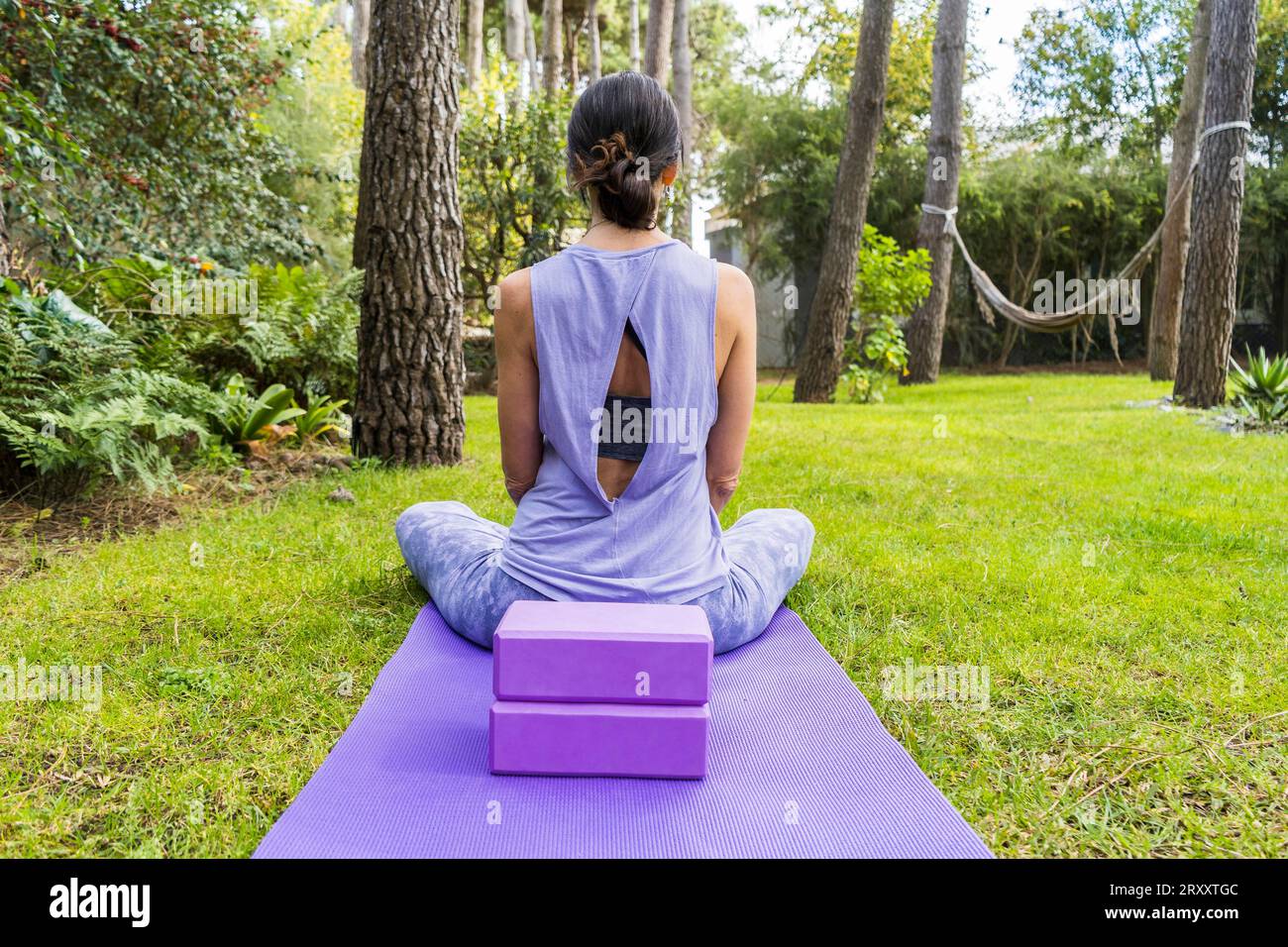 Vue arrière d'une femme en sportswear assise sur son tapis de yoga Banque D'Images