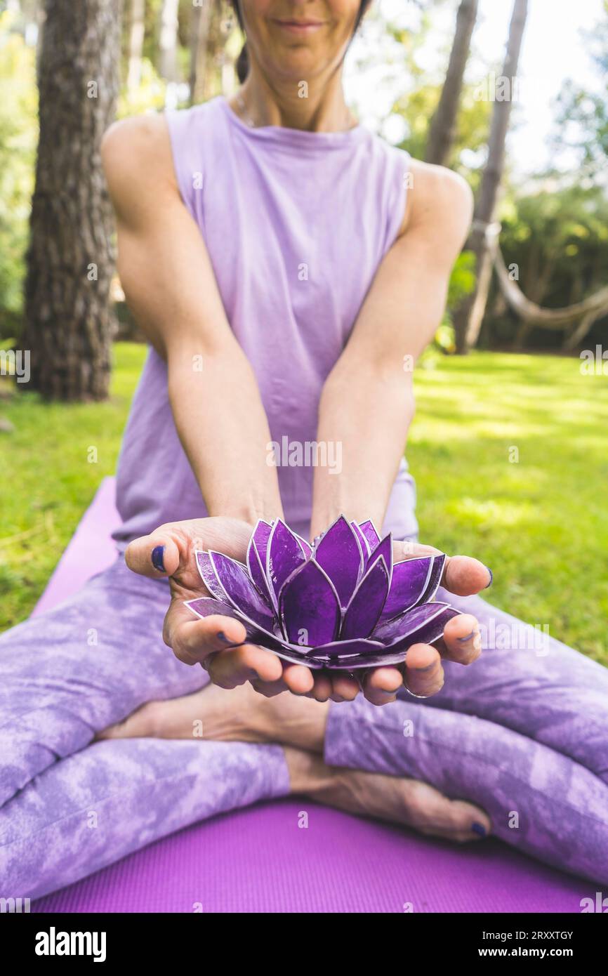 Une femme offrant un lotus en verre violet. Concept de yoga et de méditation Banque D'Images