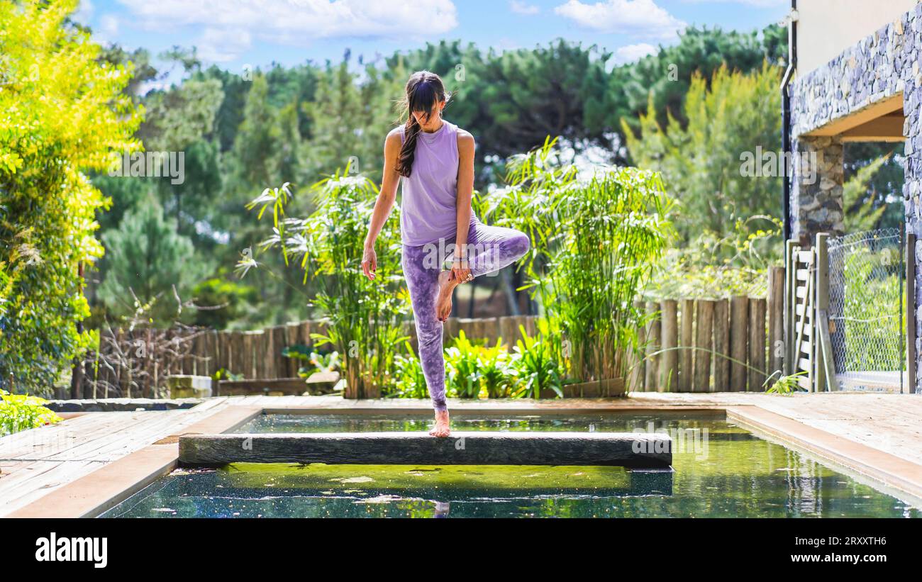 Femme adulte moyenne pratiquant le yoga sur une piscine Banque D'Images