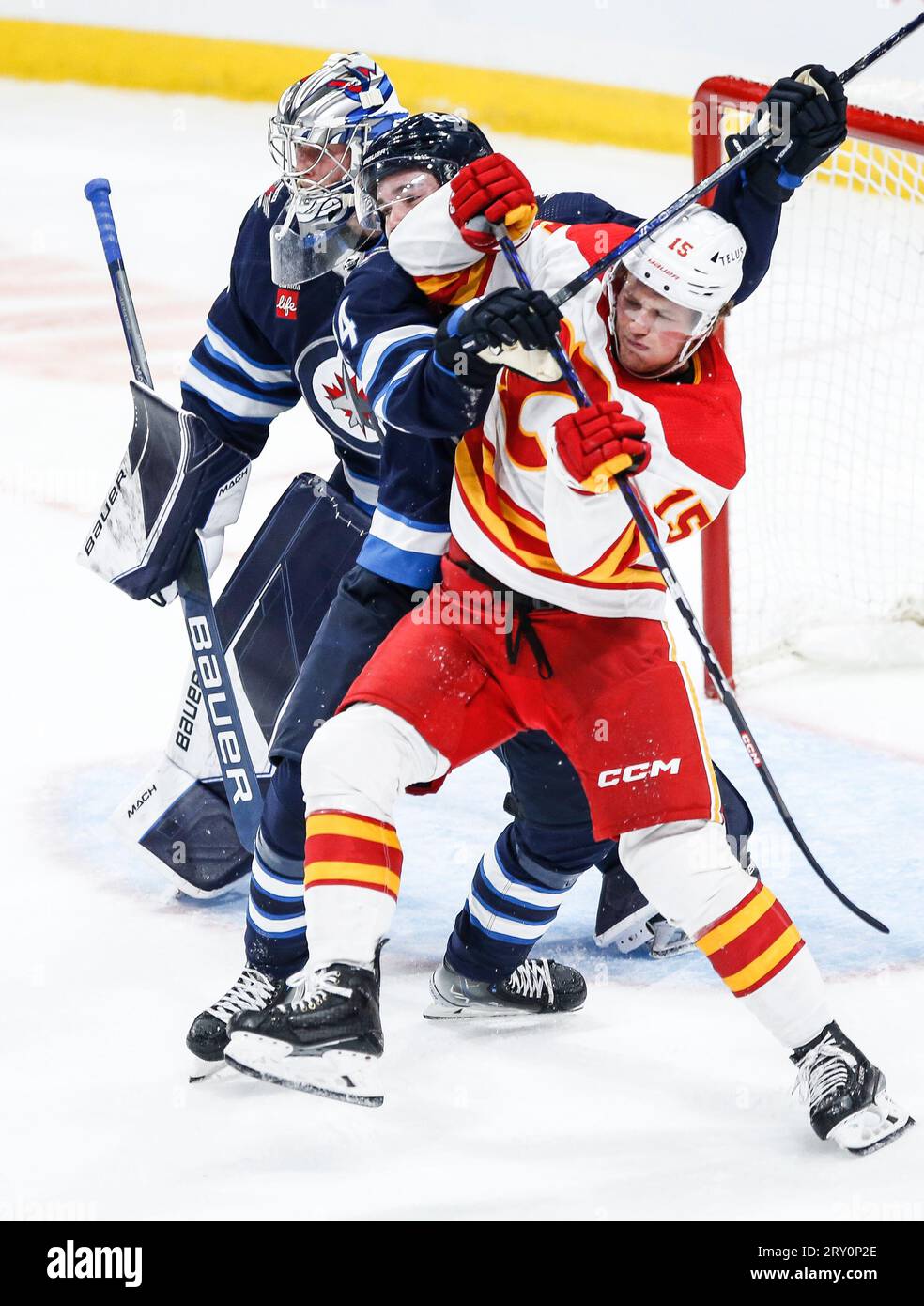 Winnipeg Jets' Ville Heinola (14) defends against Calgary Flames' Dryden Hunt (15) during the third period of an NHL hockey preseason game Wednesday, Sept. 27, 2023, in Winnipeg, Manitoba. (John Woods/The Canadian Press via AP) Banque D'Images