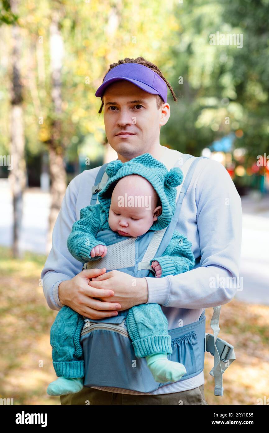 Jeune père avec son nouveau-né dans une écharpe dans le parc. Banque D'Images