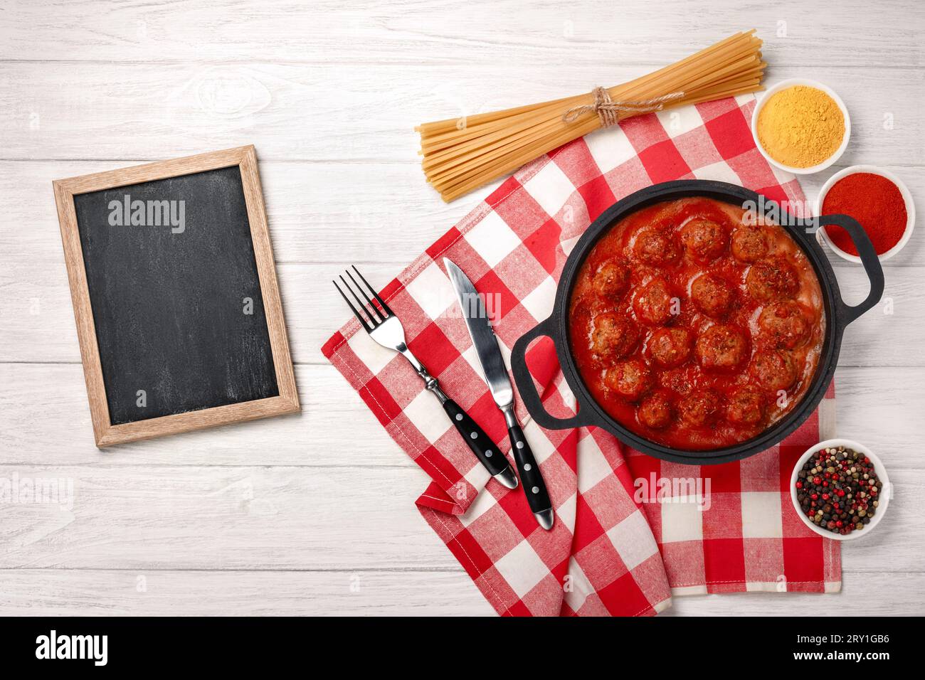Boulettes de viande à la sauce tomate avec des épices dans une poêle sur une planche de bois blanche. Vue de dessus avec espace pour votre texte. Banque D'Images