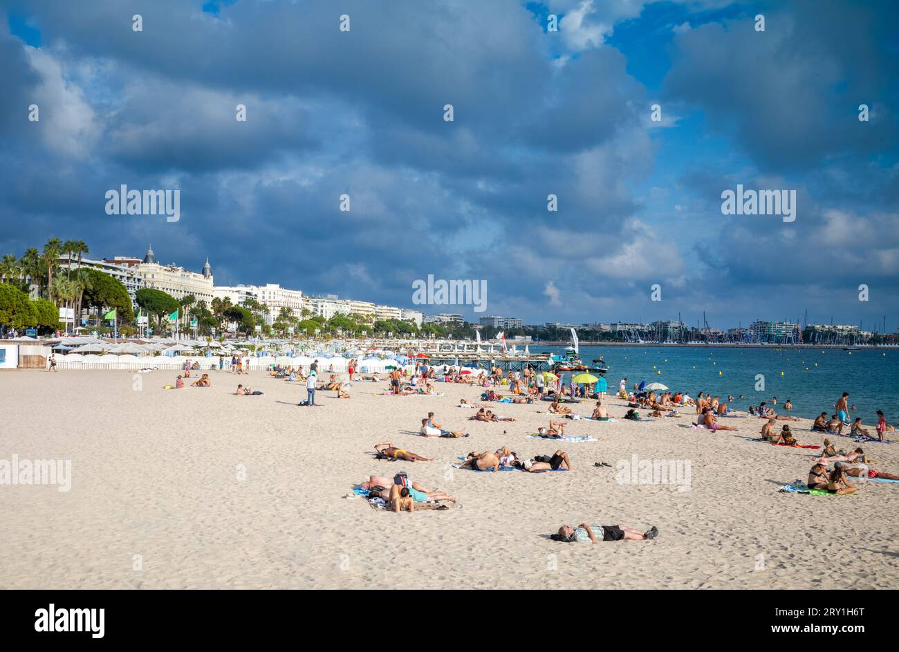 Les gens se détendent sur la plage publique de Mace (Plage Macé) en fin d'après-midi à Cannes sur la Côte d'Azur dans le sud de la France. L'emblématique Carlton Ho Banque D'Images