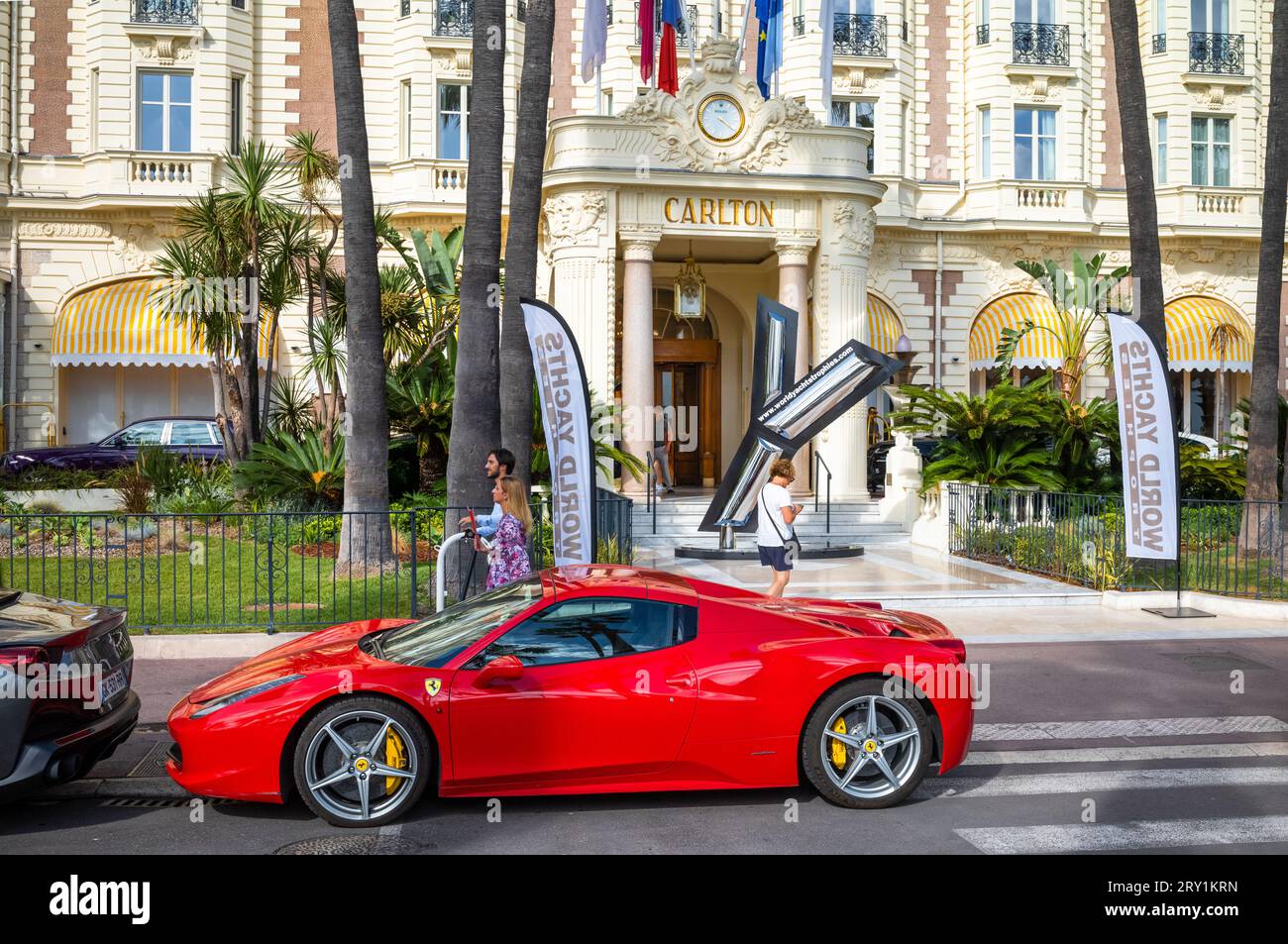 Une voiture de sport Ferrari rouge garée devant le luxueux hôtel Carlton situé sur le boulevard de la Croisette, juste en face de la mer Méditerranée Banque D'Images