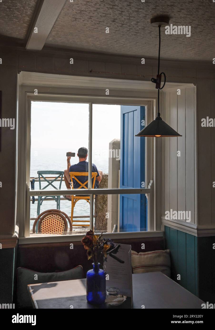 Un visiteur à l'extérieur du Devonport Inn at Kingsand reste en contact tout en se relaxant à côté de Cawsand Bay Banque D'Images