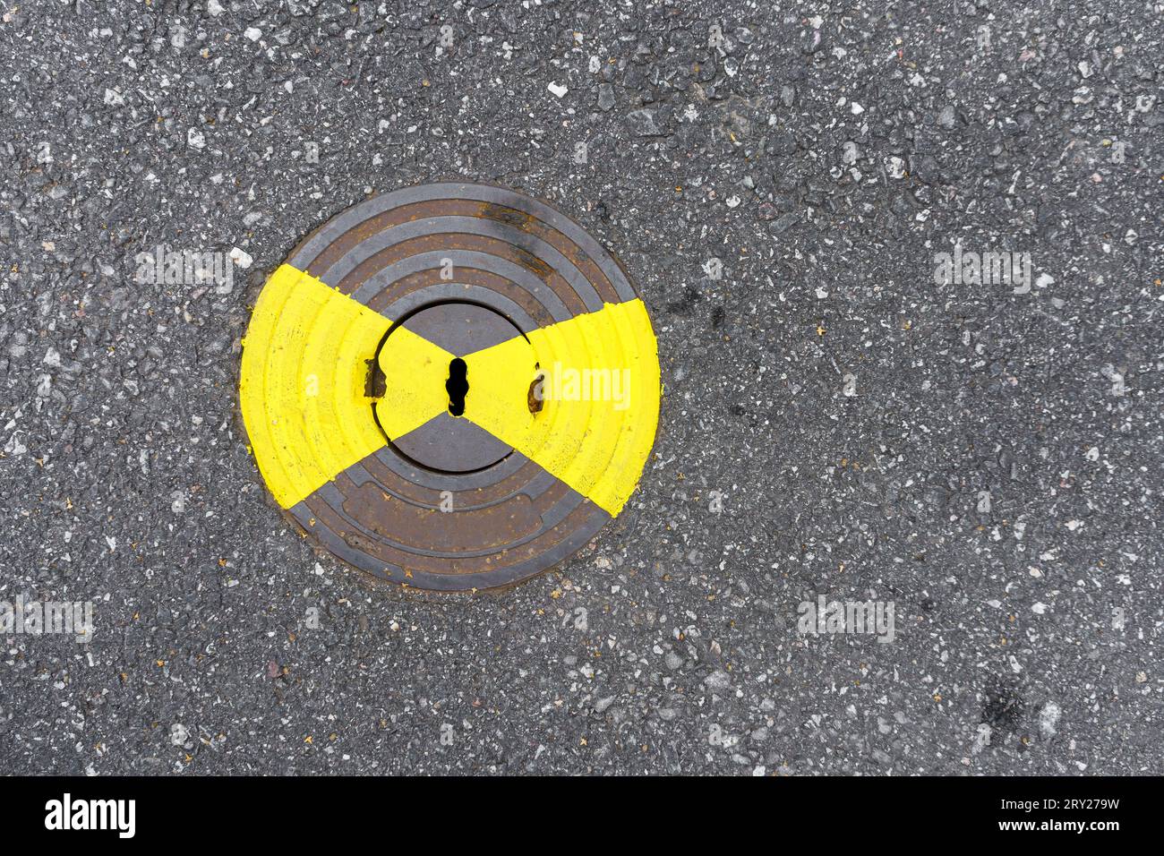 Couvercle de trou d'homme utilitaire de gaz avec peinture jaune sur asphalte, vue de dessus. Banque D'Images