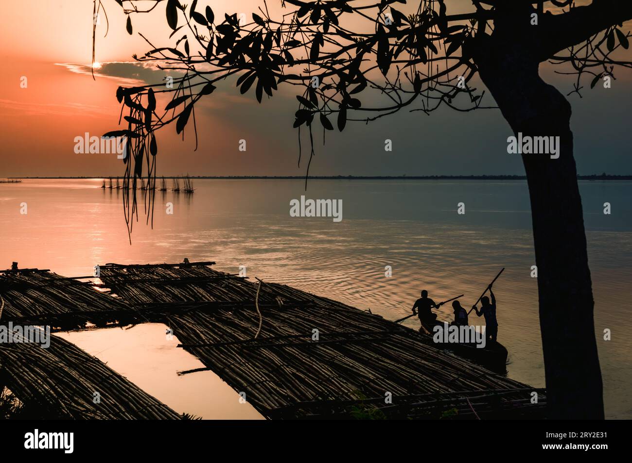 Coucher de soleil sur la rivière. Pêcheurs au coucher du soleil, rivière Brahmapoutre. Dibrugarh, Assam, Inde. Banque D'Images