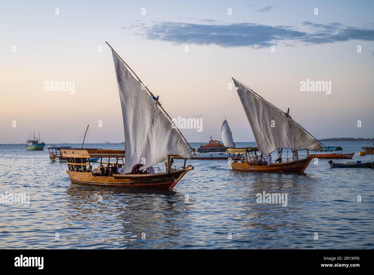 Bateaux traditionnels revenant au port au coucher du soleil à Stone Town, Zanzibar, Tanzanie Banque D'Images