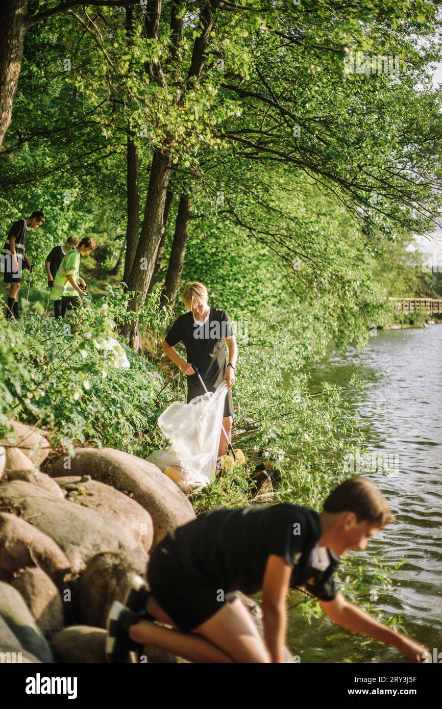 Des adolescents ramassant des ordures au bord du lac Banque D'Images