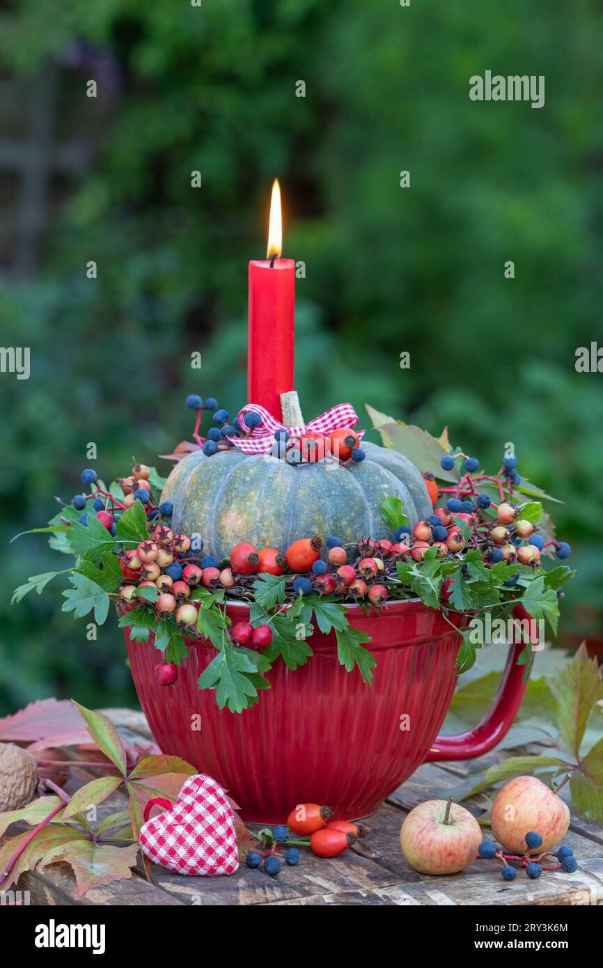 arrangement d'automne avec une bougie, une citrouille et une couronne de feuilles, des hanches roses, des baies de virginia creeper et des pommes de crabe Banque D'Images