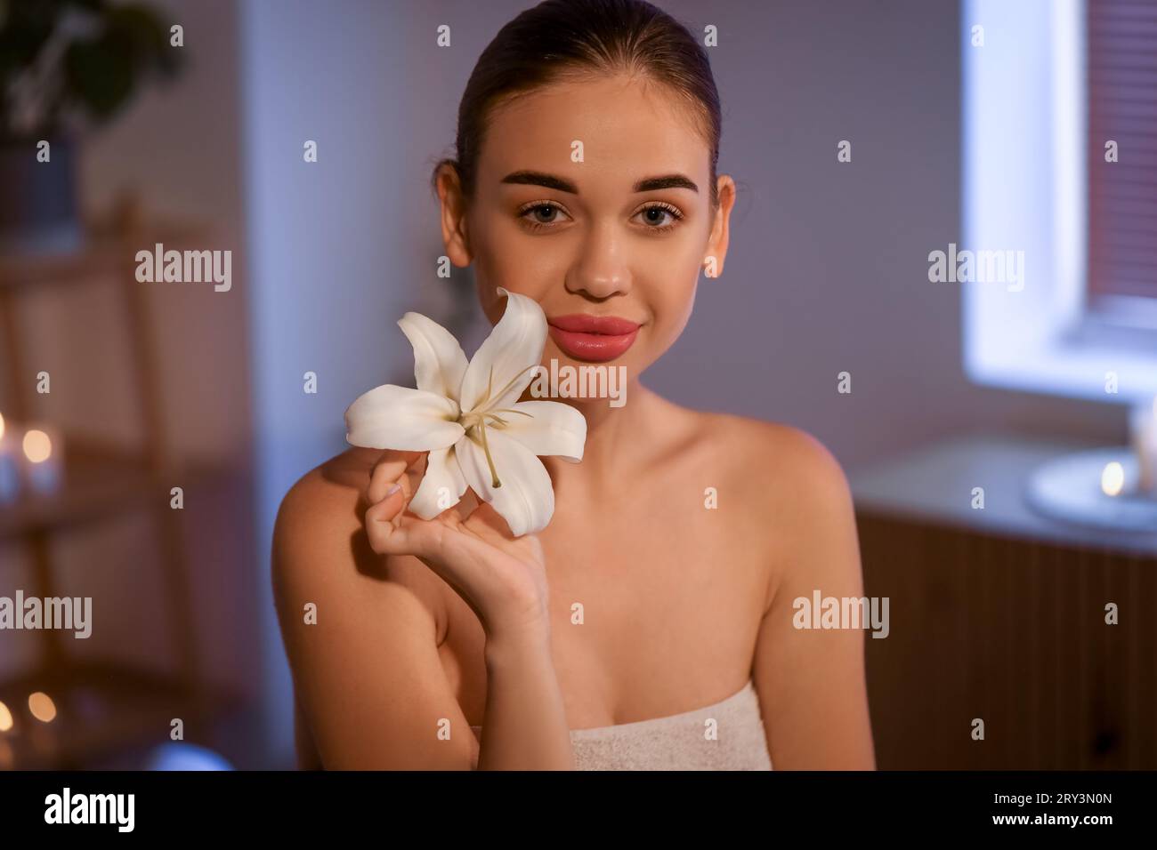 Jolie jeune femme avec fleur de lys dans le salon de spa Banque D'Images