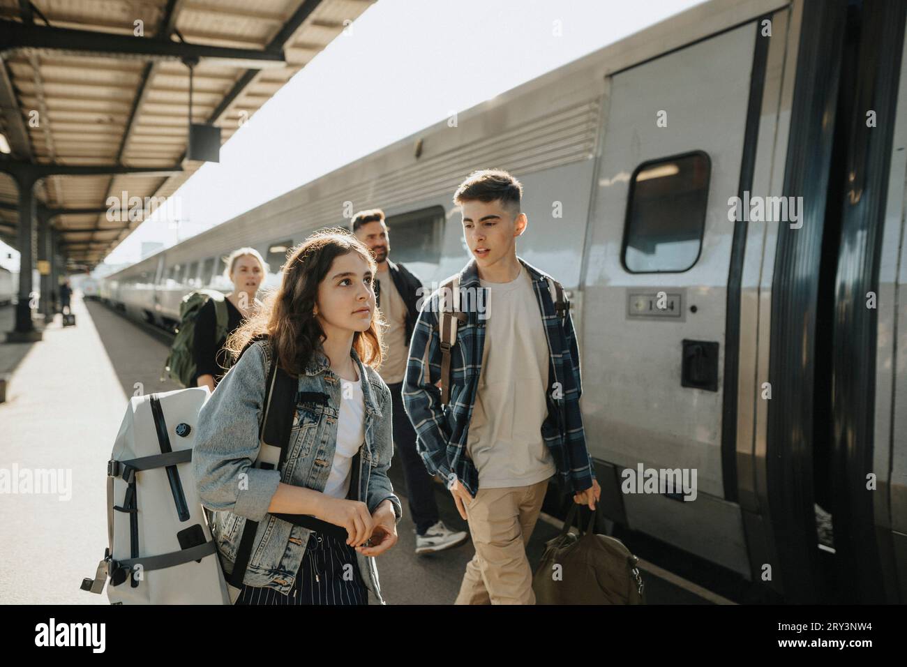 Garçon parlant à la fille portant des bagages tout en allant en vacances Banque D'Images