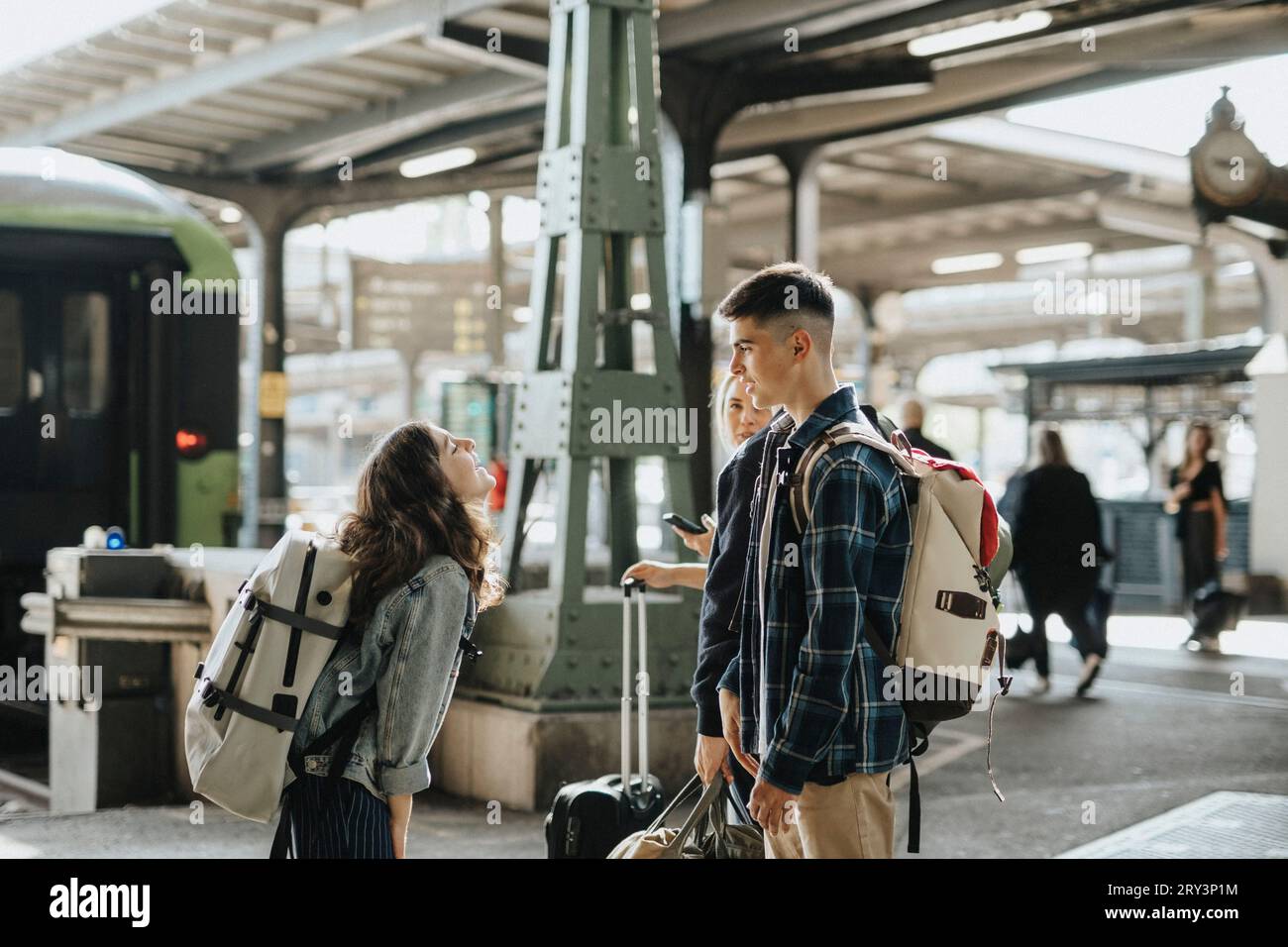 Vue de côté de la fille parlant à frère tout en se tenant à attendre le train à la gare Banque D'Images