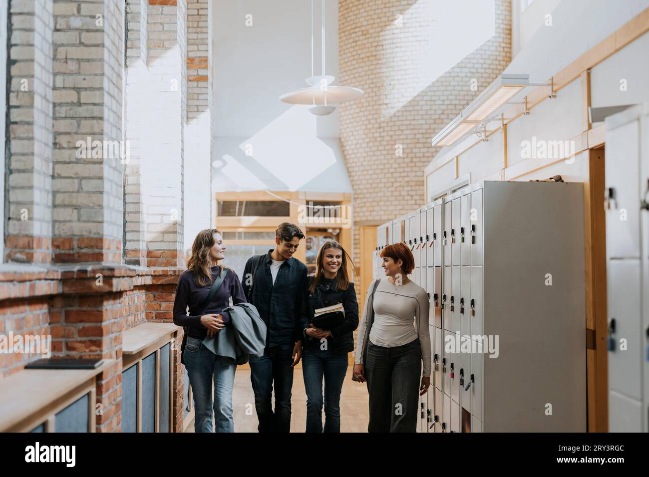 Heureux amis marchant par casier dans le couloir de l'école Banque D'Images