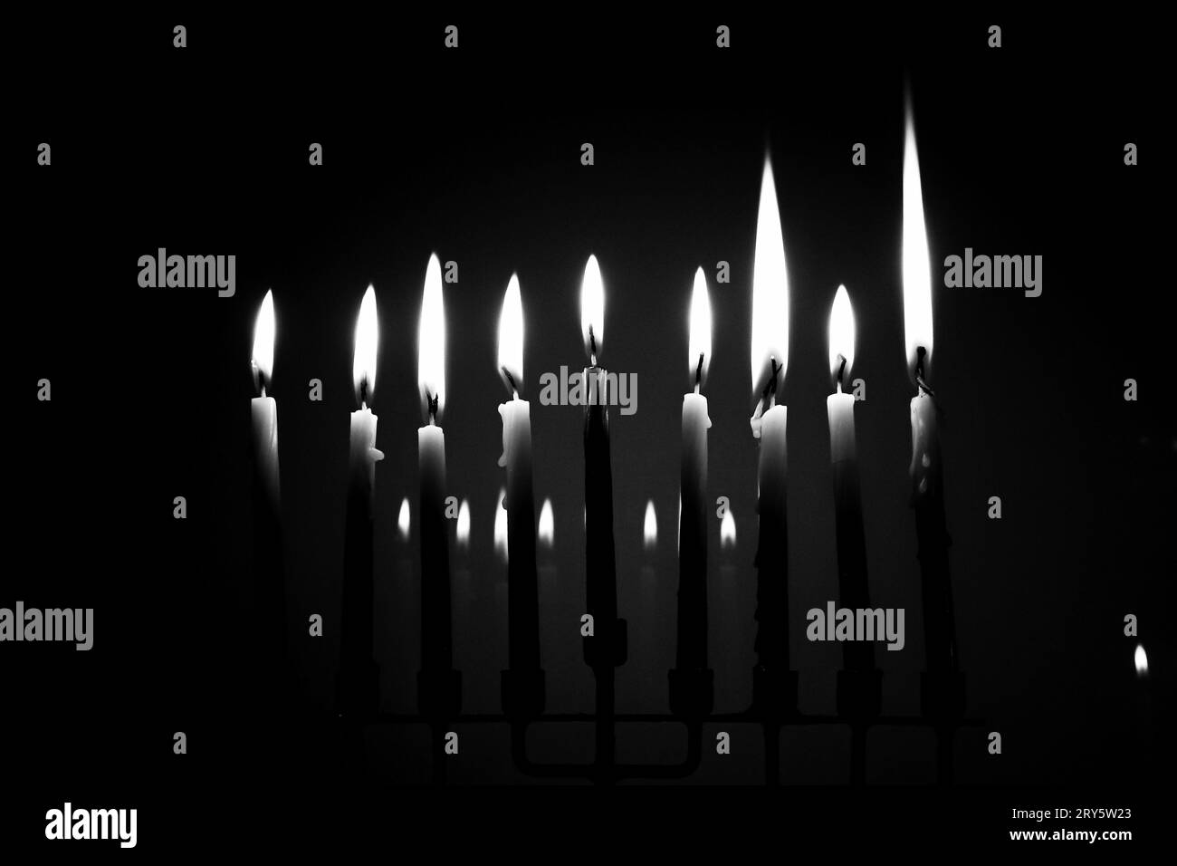 Menorah pleine en noir et blanc la dernière nuit de Hanukkah. Les neuf bougies sont allumées dans une pièce sombre et se reflètent en arrière-plan. Concept de vacances Banque D'Images