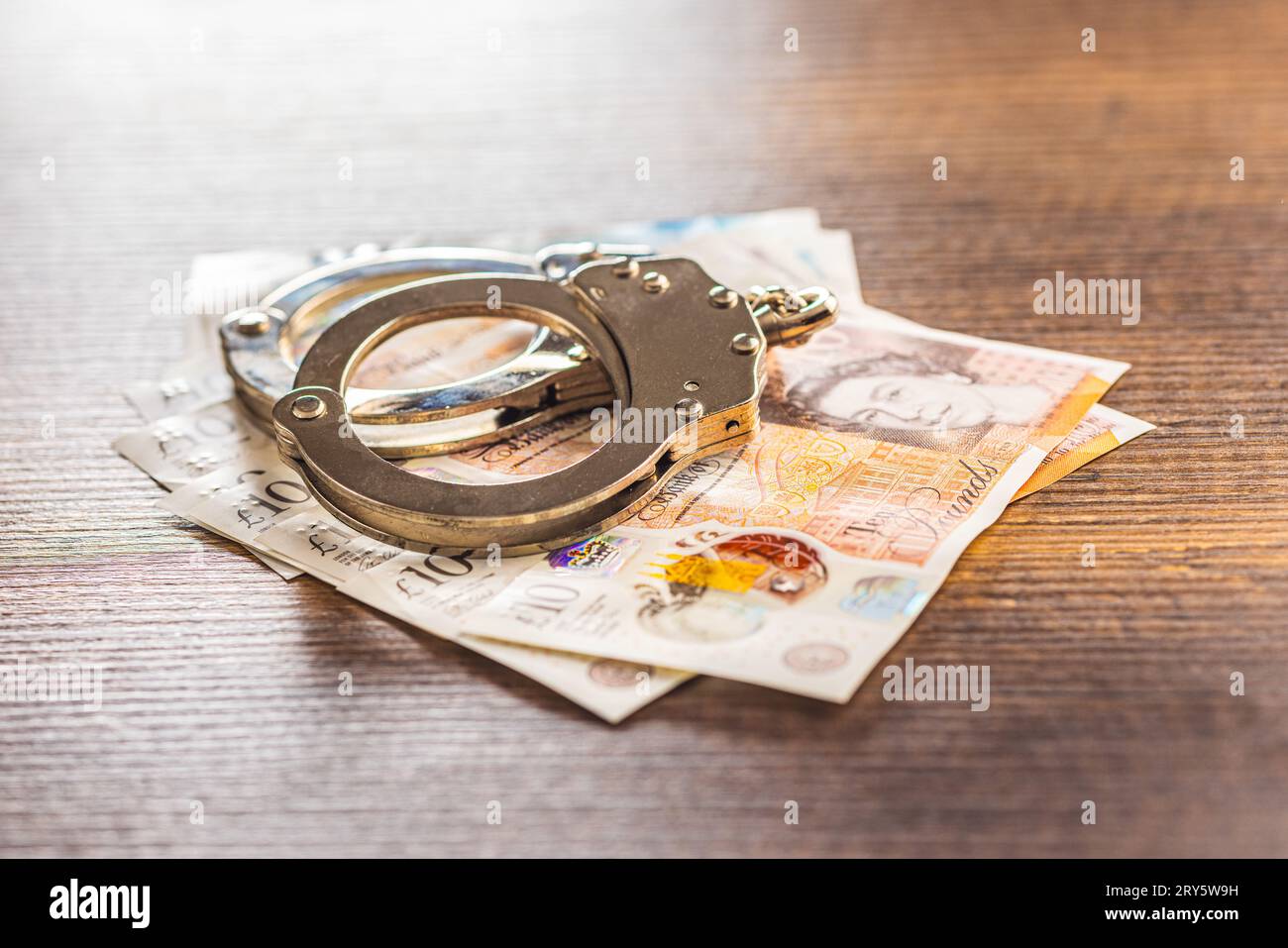 Menottes et livre sterling sur la table en bois. Banque D'Images