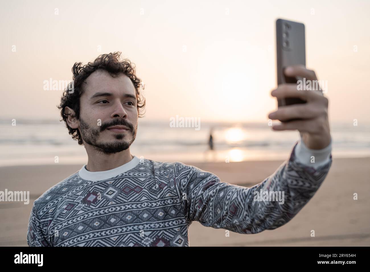 Jeune homme prend une photo selfie sur la plage au coucher du soleil Banque D'Images