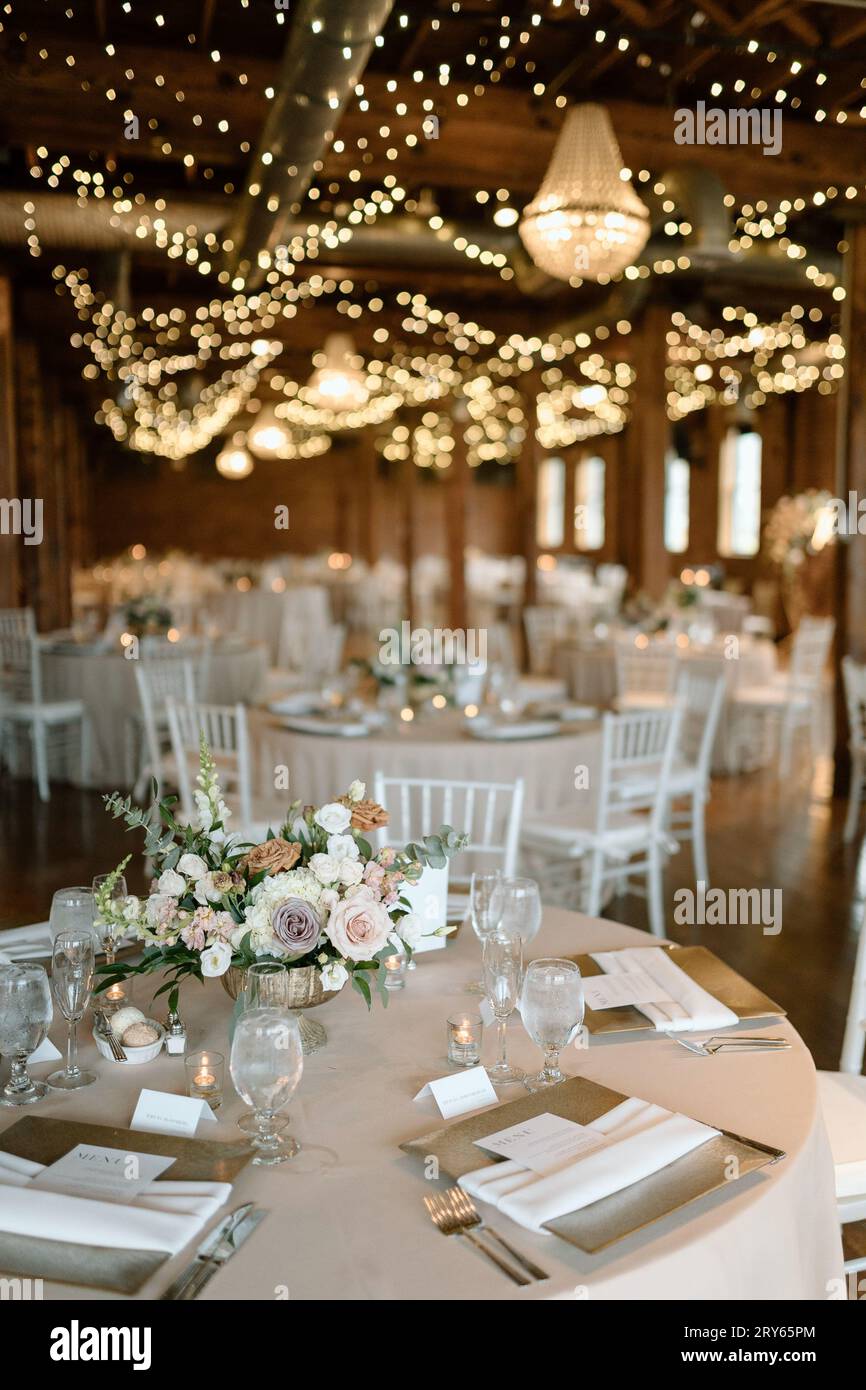 Réception de mariage élégante ; tables blanches, plafonniers scintillants. Banque D'Images