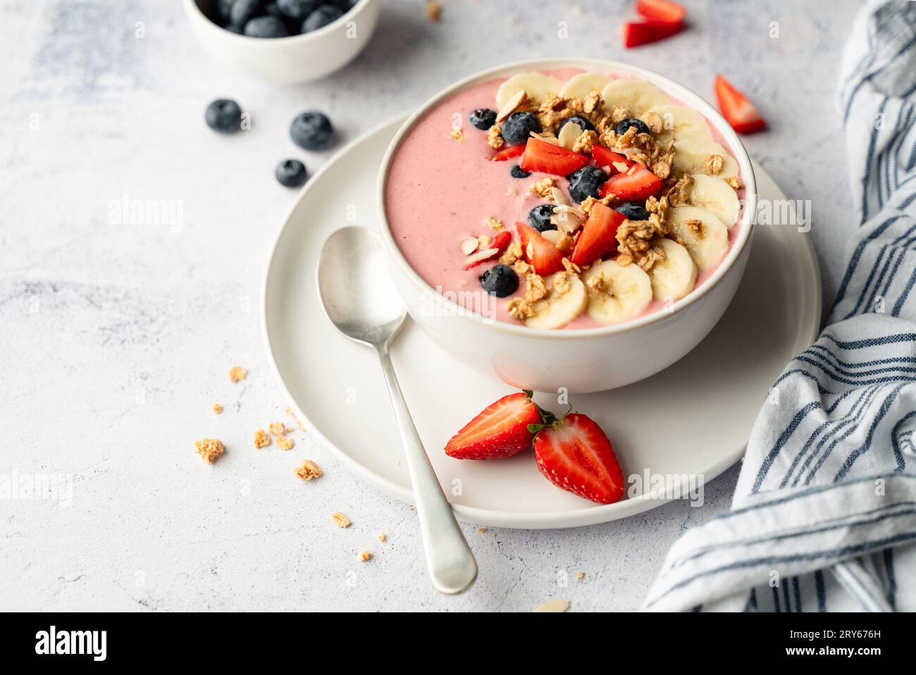 Gros plan du bol de smoothie avec des fruits et granola sur fond gris. Banque D'Images