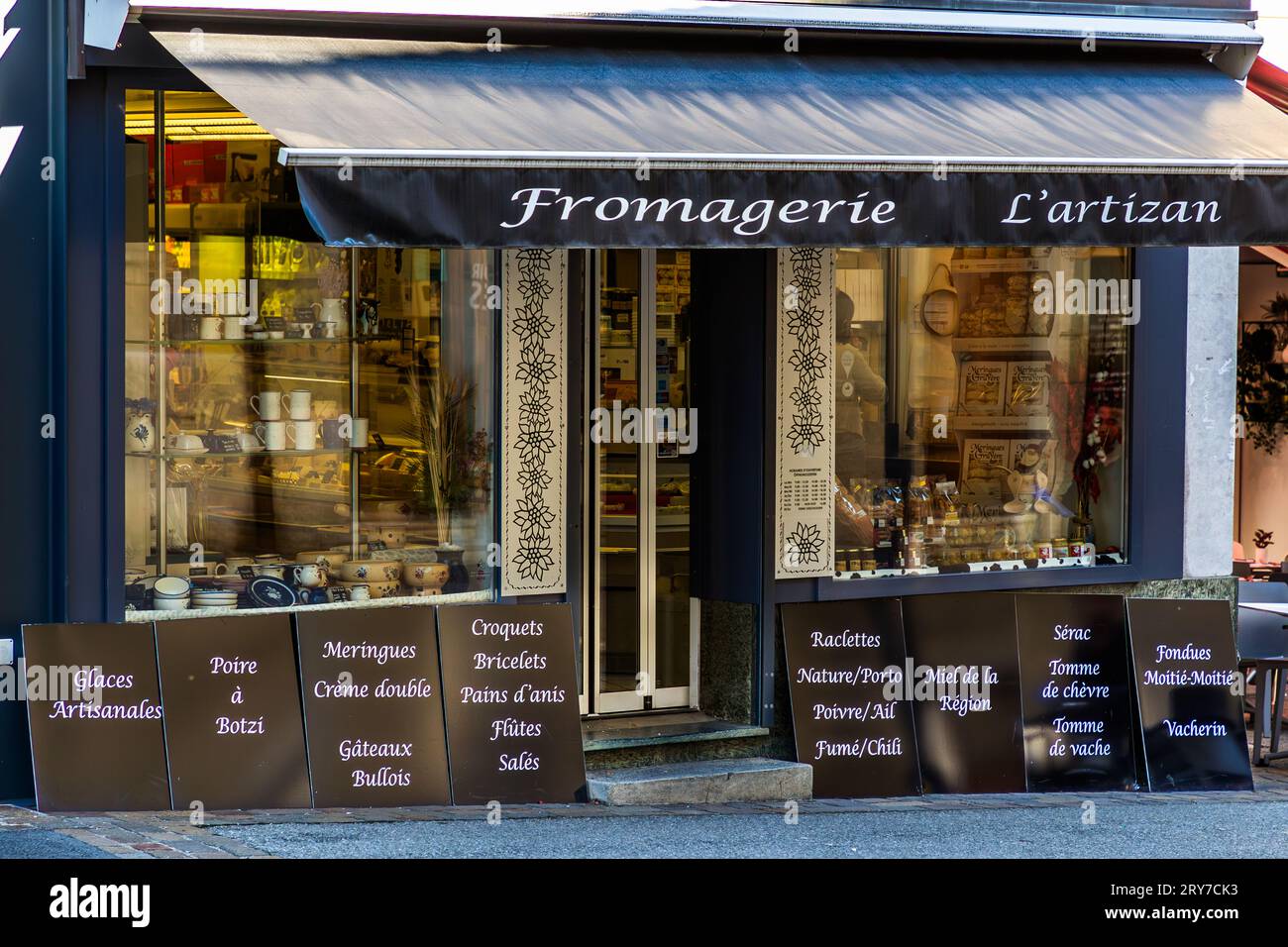 La charcuterie et fromagerie L'Artizan au 83 rue de Lausanne dans le centre de Fribourg, en Suisse, propose presque toutes les spécialités de la région, du pain à l'anis au Vacherin, de la double crème aux meringues. Des panneaux manuscrits à l'extérieur de la boutique énumèrent la Poire à Botzi, les croquets, la fondue moitié-moitié et le Gruyère. Banque D'Images