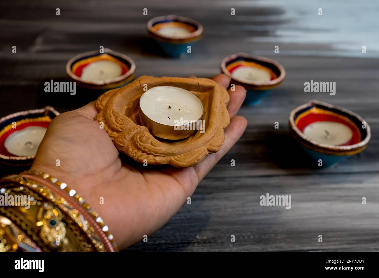 Happy Diwali - femmes mains avec henné tenant la bougie allumée isolé sur fond sombre. Clay Diya lampes allumées pendant Dipavali, festival hindou de lumières ce Banque D'Images