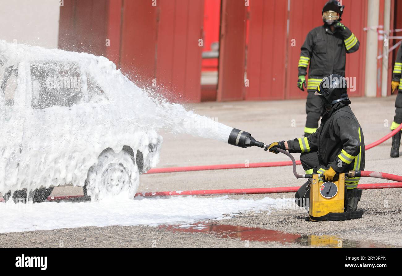 les pompiers éteignent le feu de voiture après le terrible accident de la route avec de la mousse blanche dense Banque D'Images