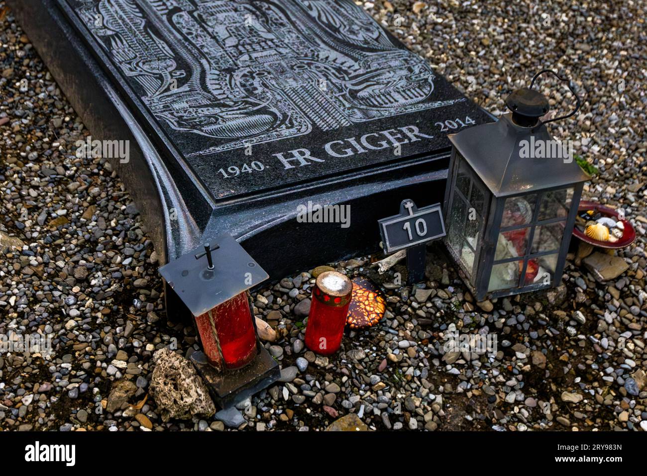 La pierre tombale de Hans-Ruedi (H. R.) Giger, 1940 à 2014, se trouve dans le cimetière de Gruyères à Épagny, canton de Fribourg, Suisse. La pierre de granit noir porte un motif de la série Biomechanoid, Biomechanical Matrix de Giger. Giger a remporté un Oscar en 1980 pour sa contribution à la conception d'Alien. Des bougies funéraires rouges, une lanterne en métal et une stèle funéraire numérotée 10 se dressent devant la pierre. Banque D'Images