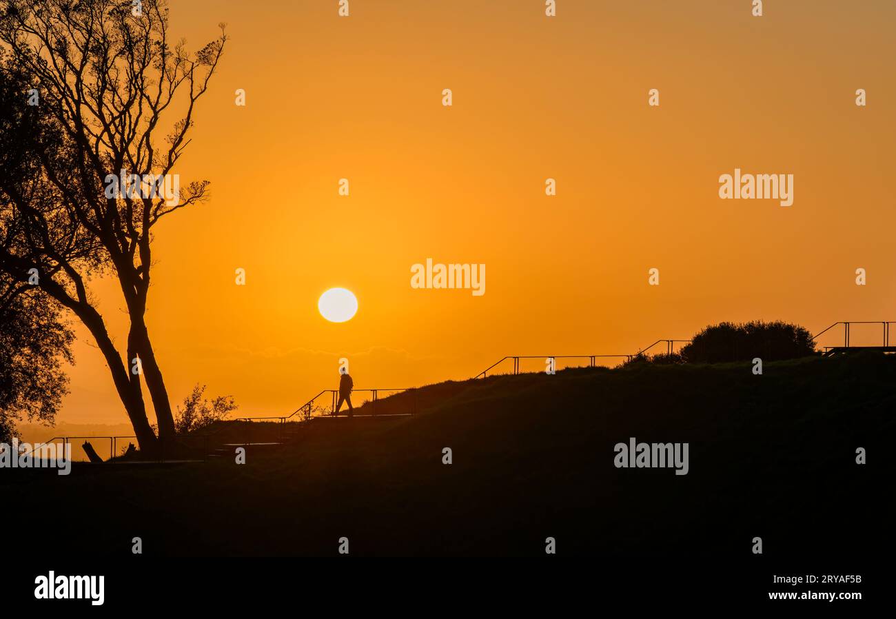Image de silhouette d'un homme marchant sur les marches de la promenade avec le soleil levant au-dessus. Sommet du Mont Eden. Auckland. Banque D'Images