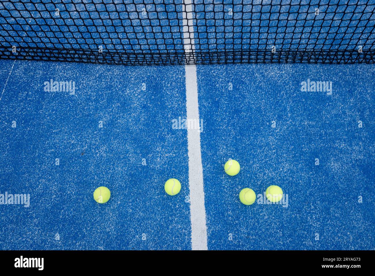 filet bleu de court de paddle tennis avec cinq balles à proximité, concept de sports de raquette Banque D'Images