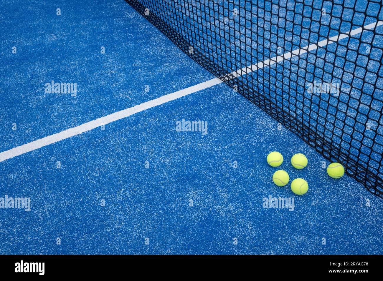 filet bleu de court de paddle tennis avec cinq balles à proximité, concept de sports de raquette Banque D'Images