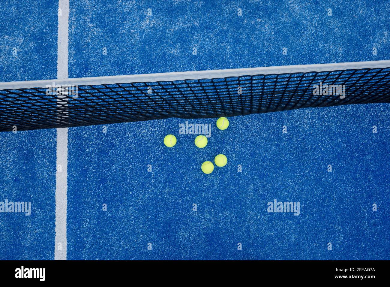 filet bleu de court de paddle tennis avec cinq balles à proximité, concept de sports de raquette Banque D'Images