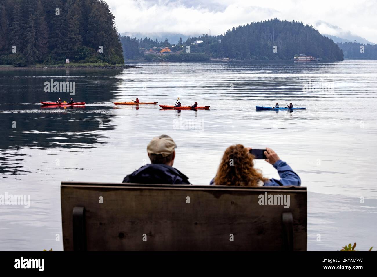 Couple assis sur un banc regardant les kayakistes à Hoonah, Alaska, USA Banque D'Images