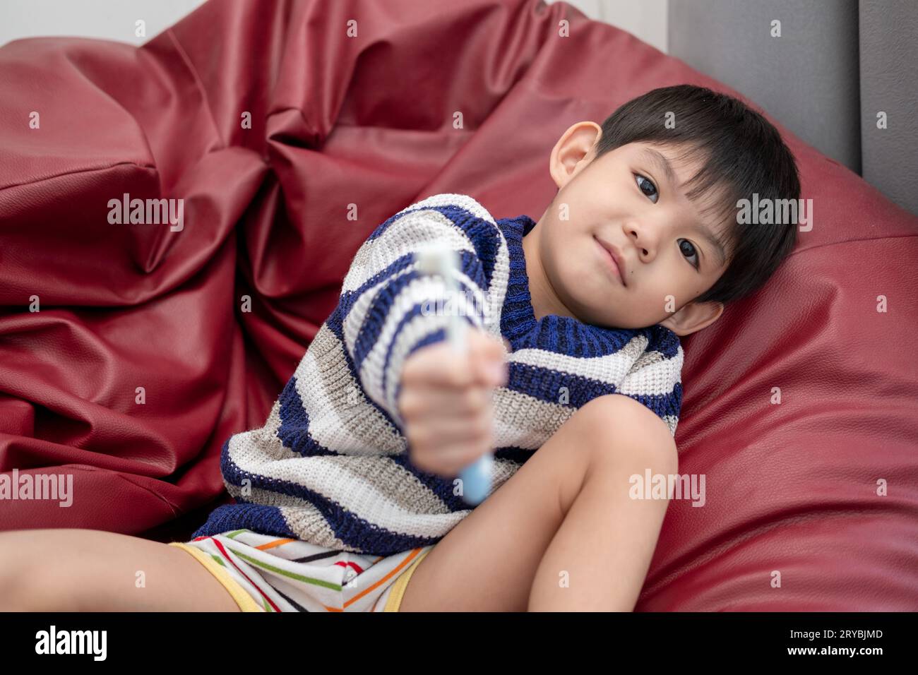 Garçon asiatique se brossant les dents sur le salon Banque D'Images