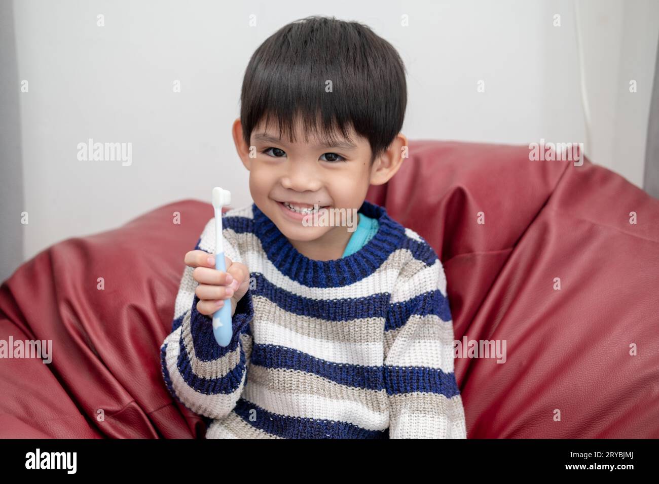 Garçon asiatique se brossant les dents sur le salon Banque D'Images