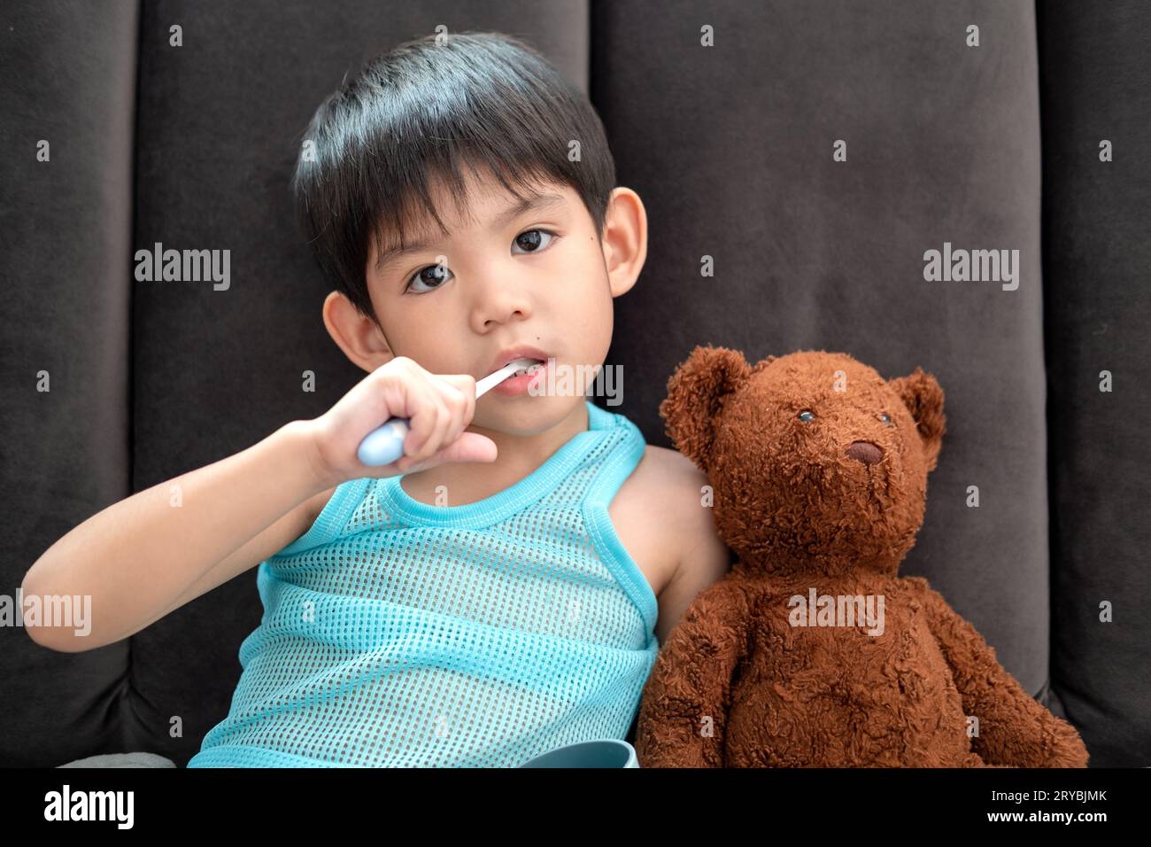 Garçon asiatique se brossant les dents sur le salon Banque D'Images