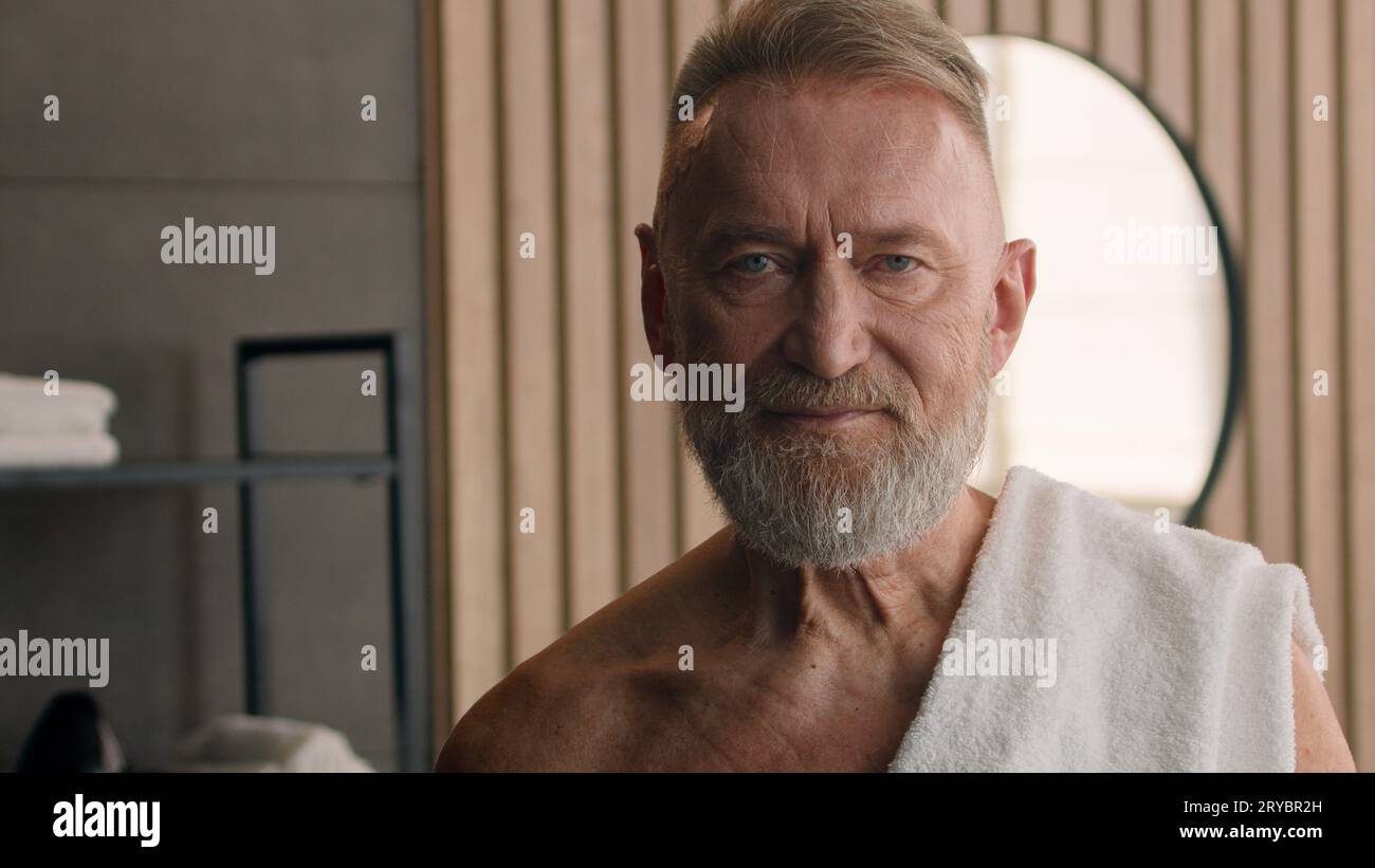 Portrait à l'intérieur dans la salle de bain dans le bain heureux personnes âgées caucasiennes vieux mâle adulte gris 70s visage mature homme sain avec serviette blanche sur Banque D'Images