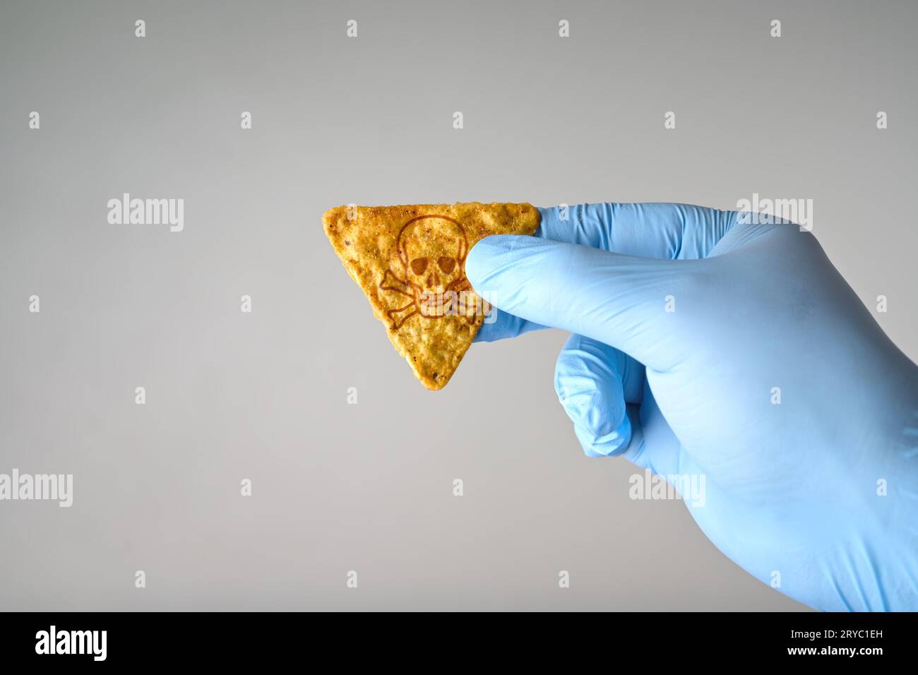 Main gantée tenant une puce de tortilla chaude avec symbole de poison. Concept pour le défi des puces chaudes. Banque D'Images