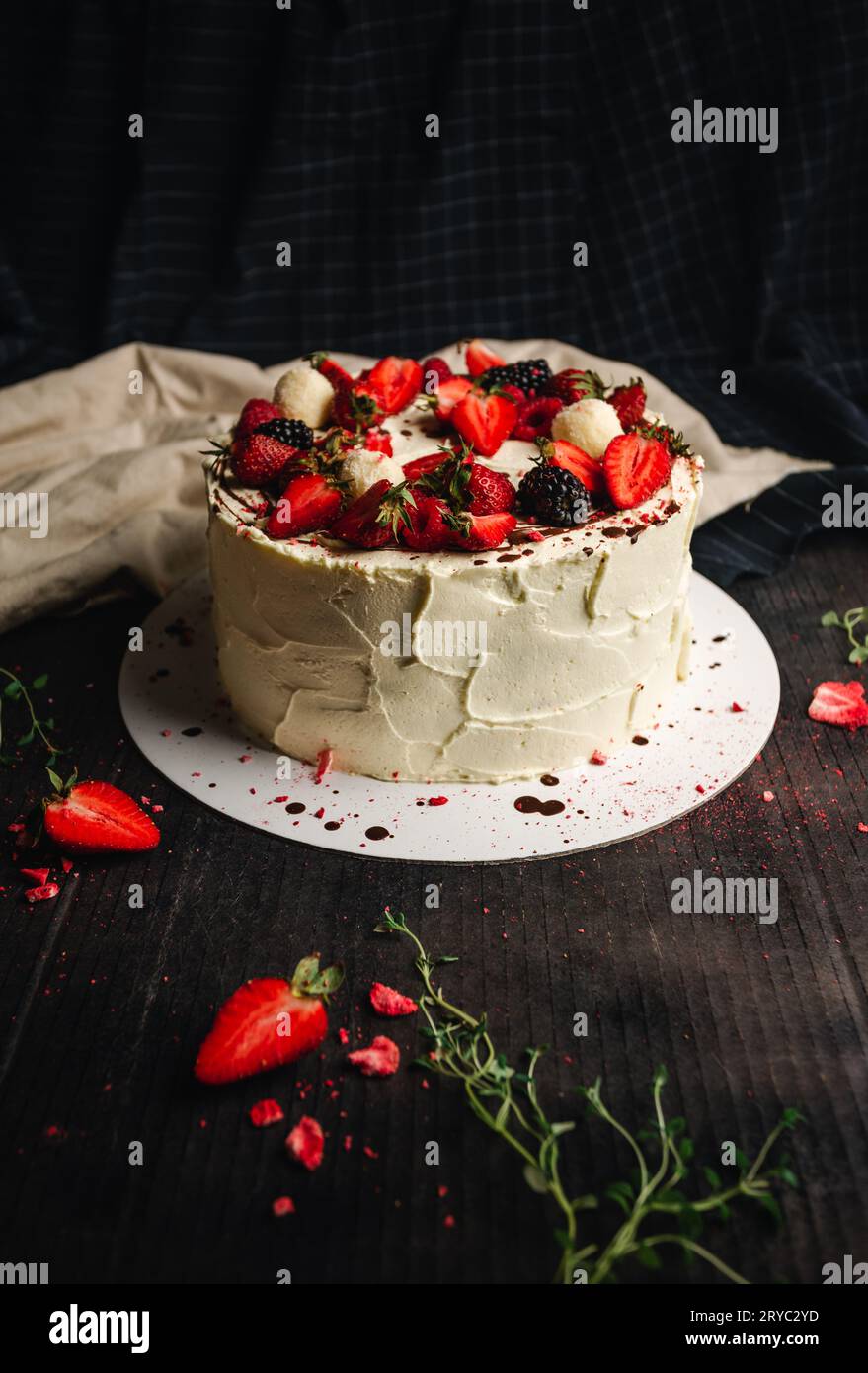 Image de gâteau Pavlova (desserts) sur fond rustique et sombre. Photographie de nourriture de grand gâteau blanc (sucré) avec des fruits à la célébration d'anniversaire ou autre Banque D'Images