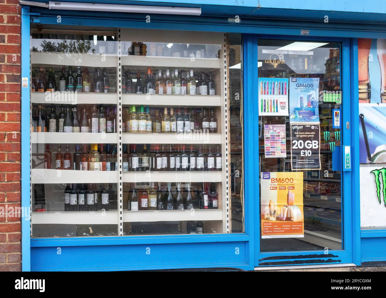 Vitrine de magasin de vins ou d'alcools dans un dépanneur, Angleterre, Royaume-Uni, avec des publicités pour vapes sur la porte Banque D'Images